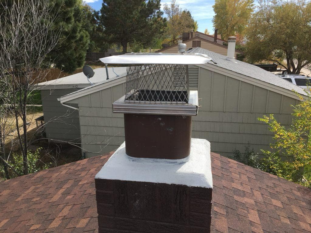Stainless steel chimney cap installed on a freshly sealed white crown