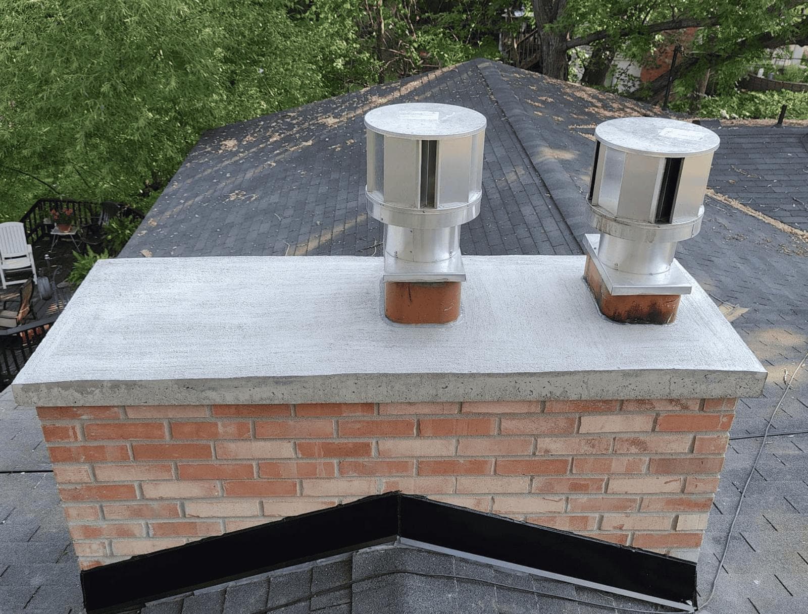 The same chimney after a new poured crown and full repointing, with two stainless steel caps installed