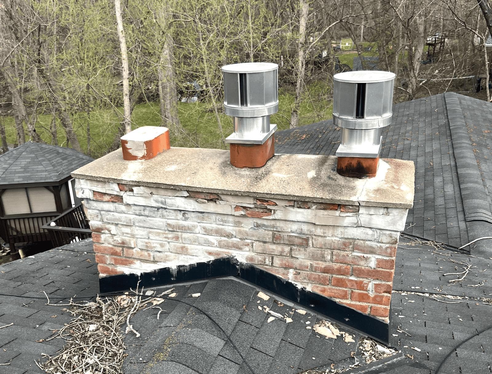 Multi-flue brick chimney with spalling brick faces and a deteriorated crown before repair