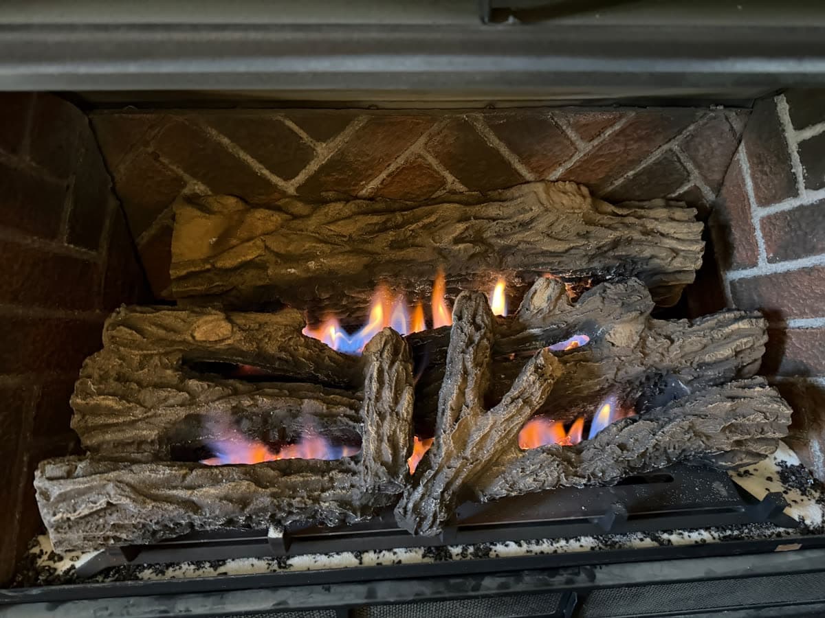 Gas log set burning in a firebox with herringbone brick panels after the logs were reset